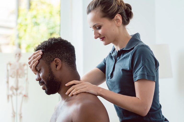 Physiotherapeutin behandelt Patienten am Nacken und Kopf